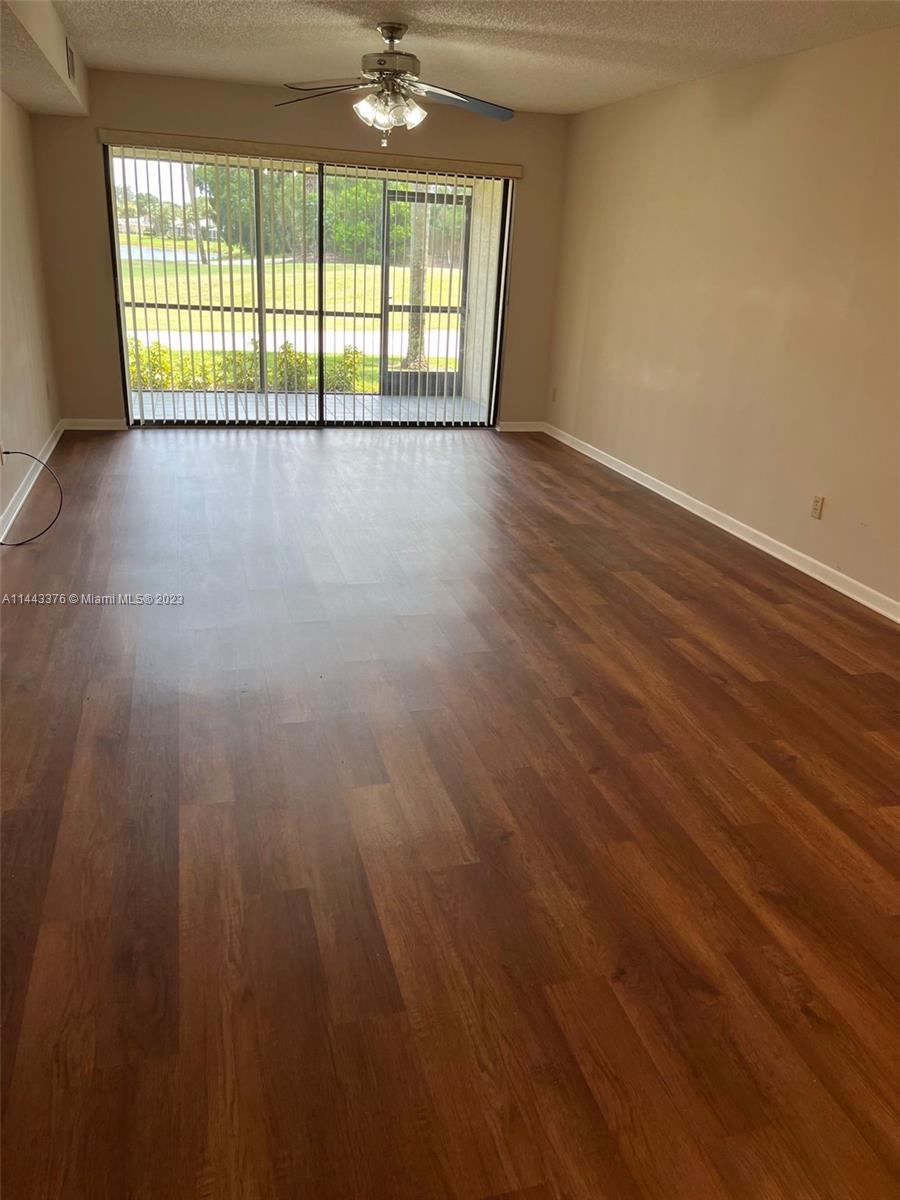 801 Pinecrest Circle, Unit E Jupiter, FL 33458 - Photo 2 of 18 an empty room with wooden floor and windows