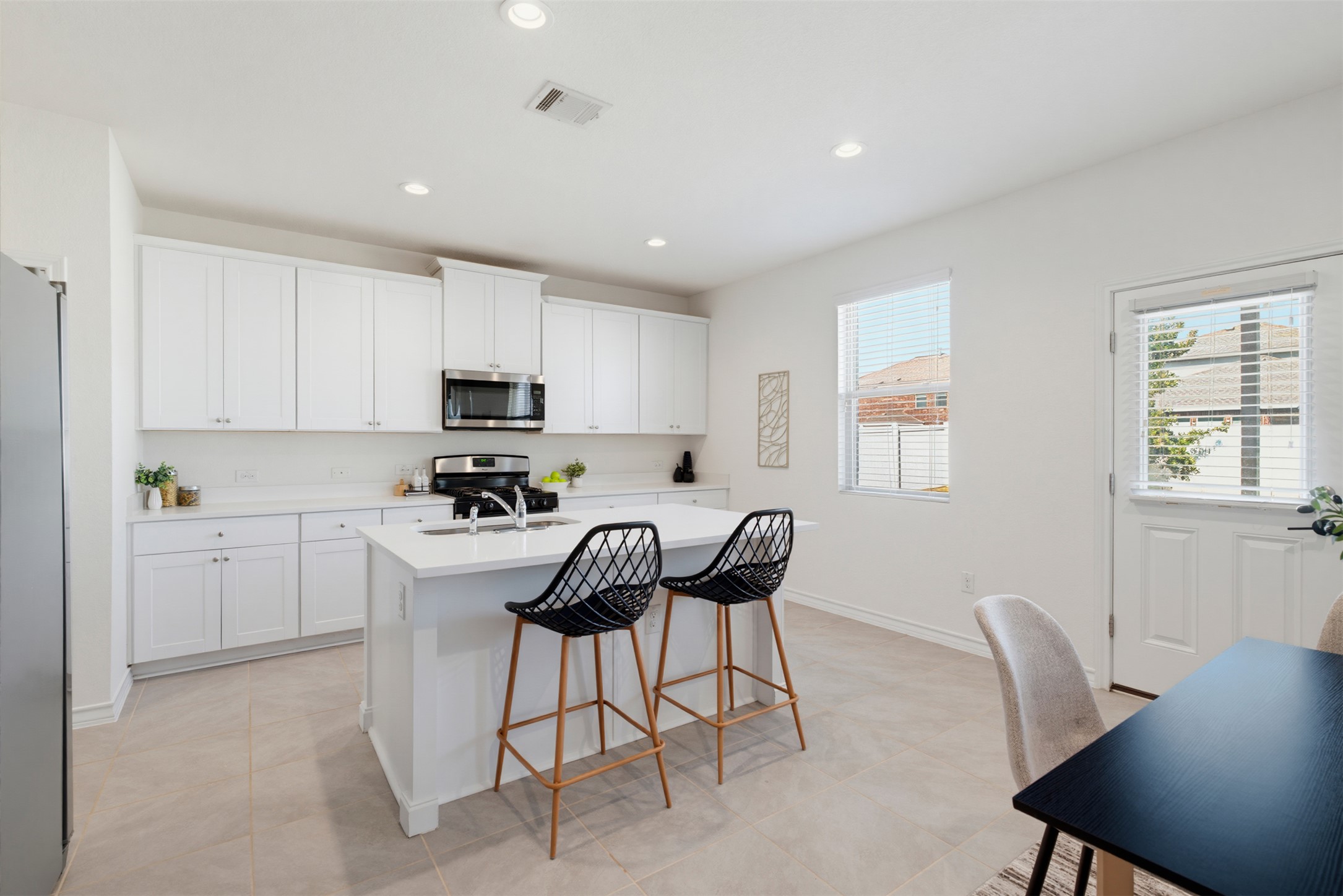 Crisp cabinetry and a generous central island anchor this modern, light-filled kitchen space.