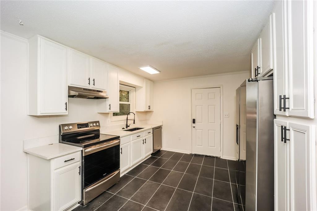 5726 Southwick Court Southwest Atlanta, GA 30349 - Photo 14 of 31 a kitchen with a sink a stove and refrigerator