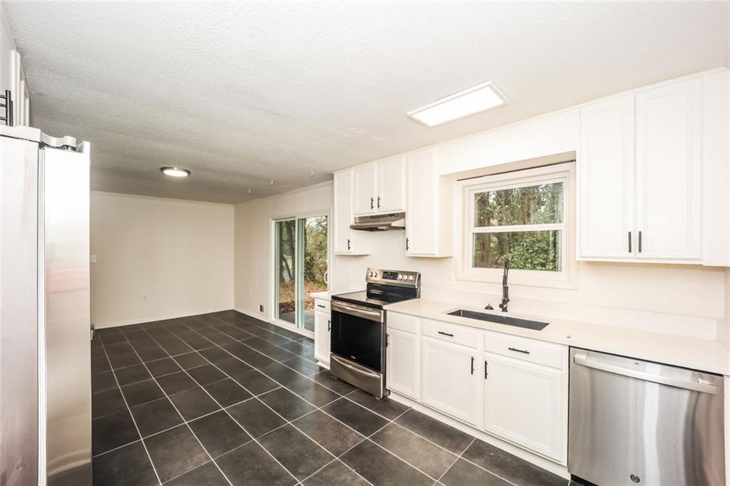 5726 Southwick Court Southwest Atlanta, GA 30349 - Photo 15 of 31 a kitchen with a sink a stove a refrigerator and white cabinets
