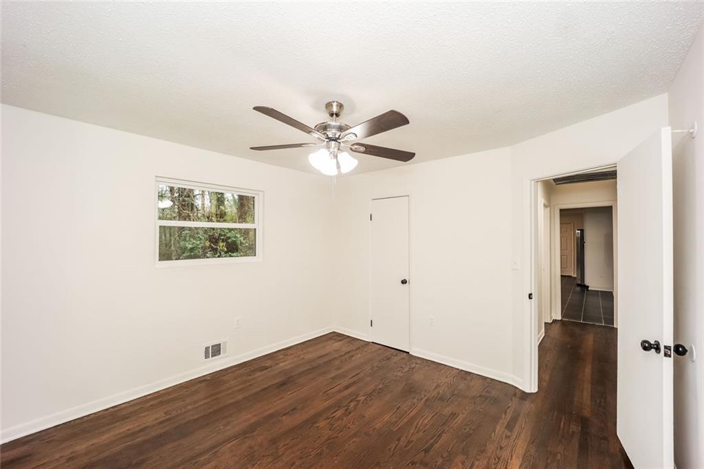 5726 Southwick Court Southwest Atlanta, GA 30349 - Photo 25 of 31 an empty room with wooden floor and ceiling fan