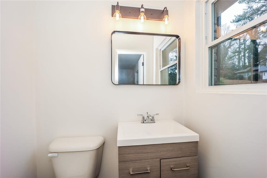 5726 Southwick Court Southwest Atlanta, GA 30349 - Photo 5 of 32 a bathroom with a toilet a sink and mirror
