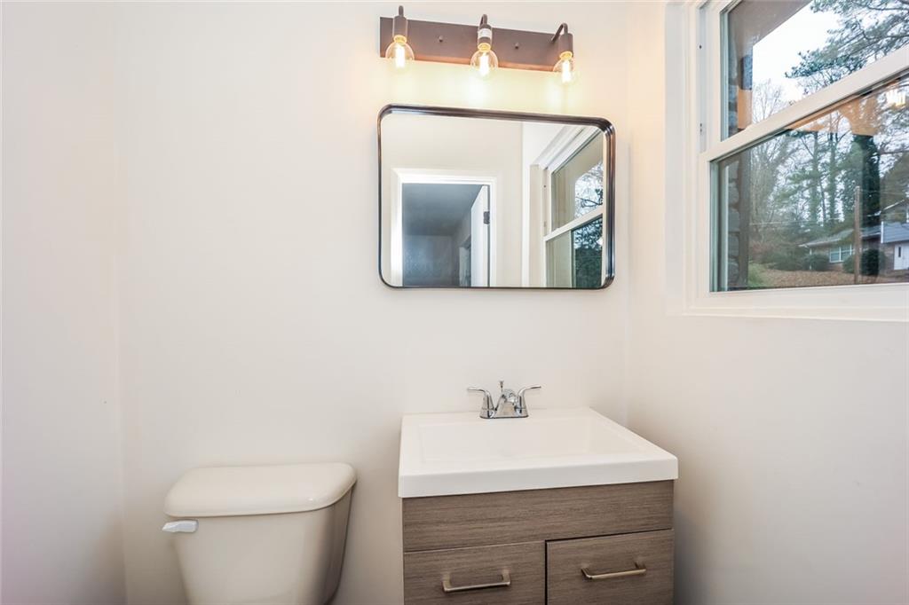 5726 Southwick Court Southwest Atlanta, GA 30349 - Photo 5 of 31 a bathroom with a toilet a sink and mirror