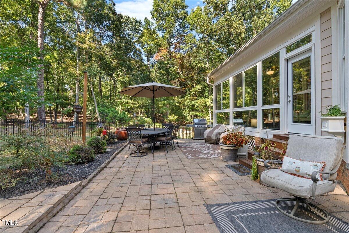 105 Jackson Road Youngsville, NC 27596 - Photo 50 of 55 a view of a patio with table and chairs under an umbrella with large trees