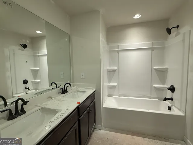 a bathroom with a granite countertop bathtub sink vanity and mirror