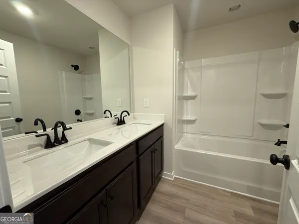 a bathroom with a tub sink double vanity and mirror
