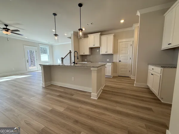 a view of a kitchen with kitchen island a sink wooden floor and a counter top space