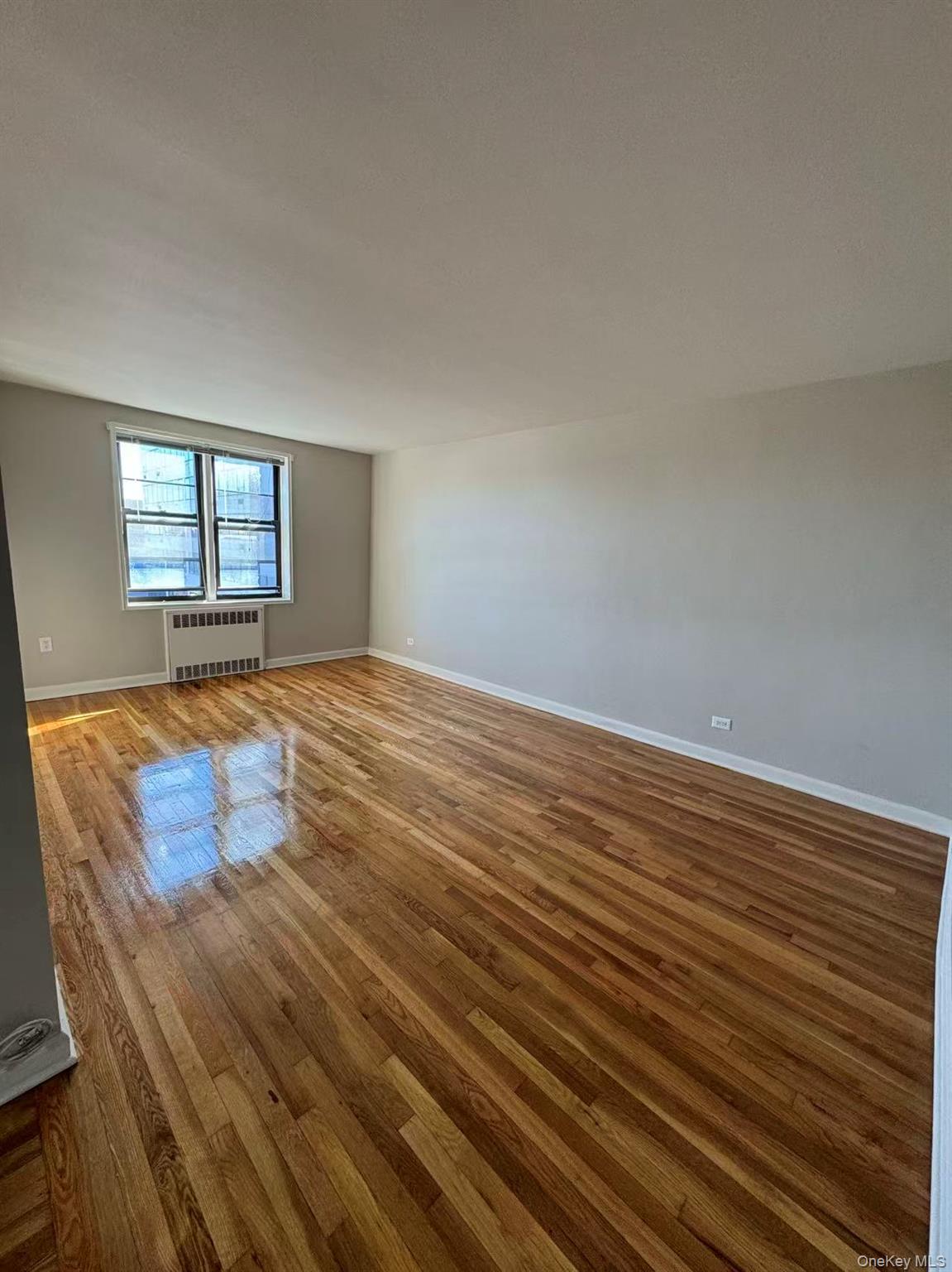 99-63 66th Avenue, Unit C14 Queens, NY 11374 - Photo 1 of 6 Spare room with wood finished floors and radiator