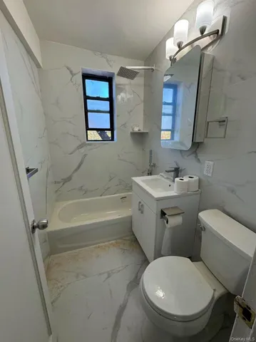 a white toilet sitting next to a bathroom sink and tub