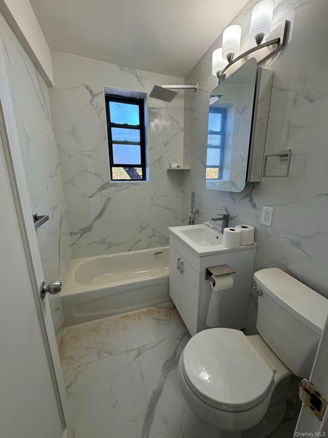 99-63 66th Avenue, Unit C14 Queens, NY 11374 - Photo 5 of 6 Full bath with light marble finish floors, vanity, a combined bath / shower with marble appearance, and tile walls