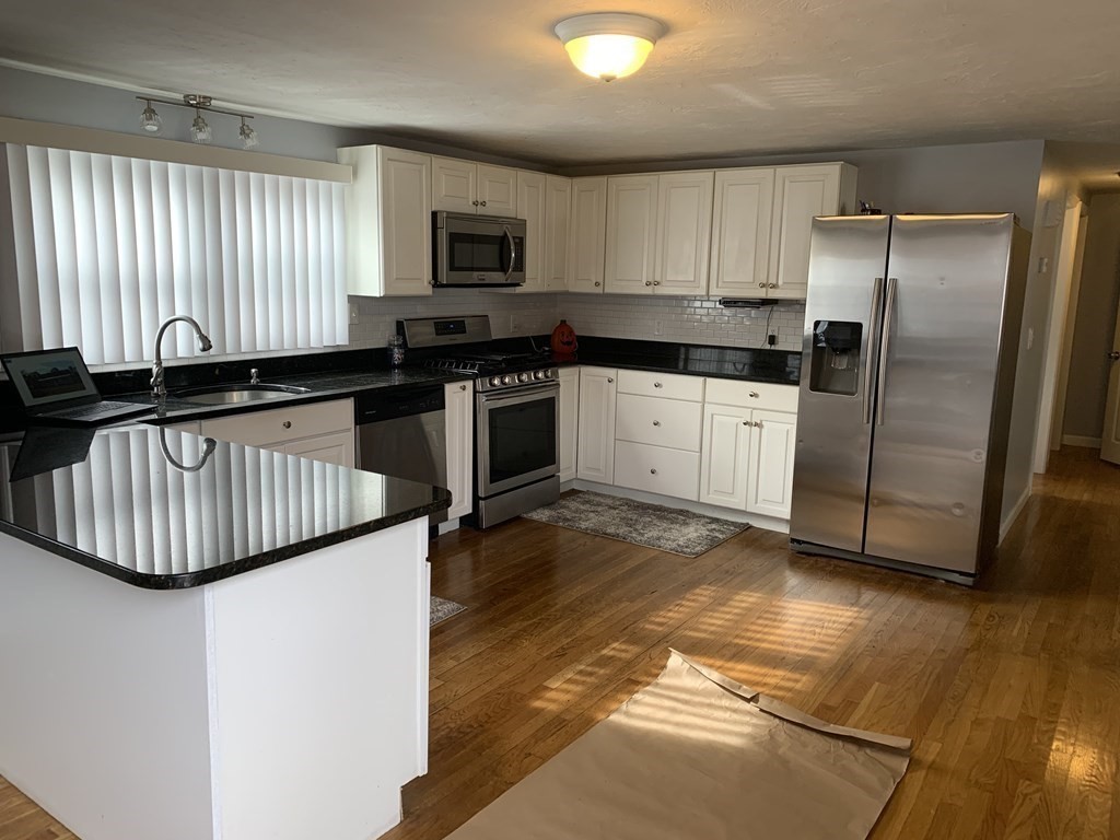 63 Lowell Road Pepperell, MA 01463 - Photo 8 of 32 a kitchen with granite countertop a stove a sink and a refrigerator