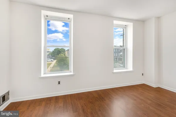an empty room with wooden floor and windows