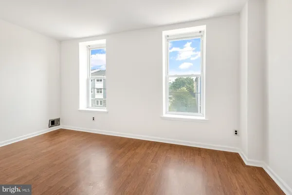 an empty room with wooden floor and windows