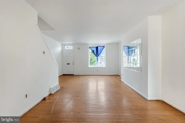 an empty room with wooden floor and windows