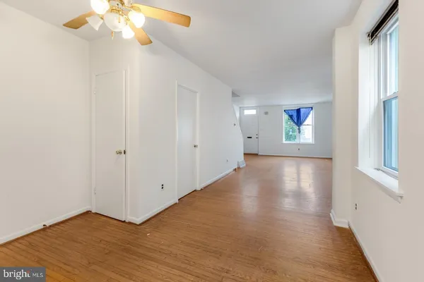 a view of an empty room with wooden floor and a window