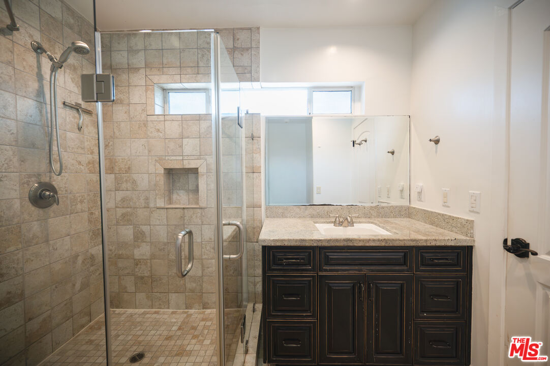 503 North Greencraig Road Los Angeles, CA 90049 - Photo 36 of 59 a bathroom with a granite countertop sink a shower and a mirror