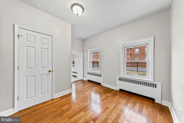 a view of an empty room with a window and wooden floor