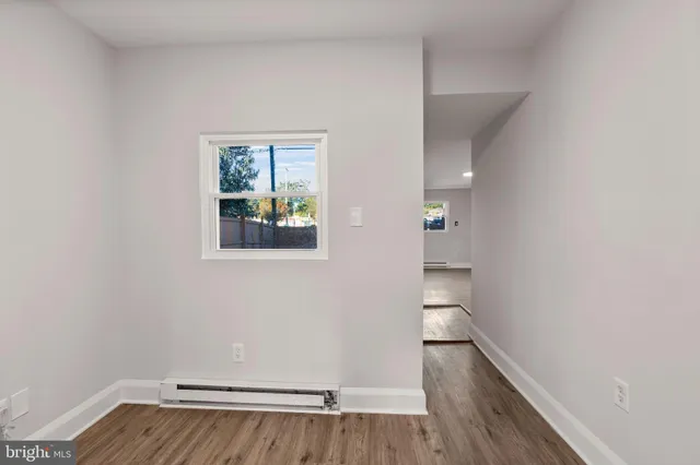 a view of empty room with wooden floor and window