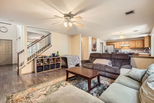 a living room with furniture kitchen view and a wooden floor