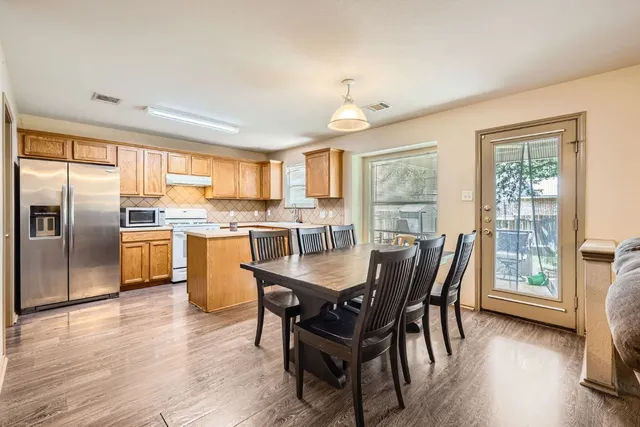 a kitchen with stainless steel appliances granite countertop a stove a refrigerator a kitchen island a table and chairs