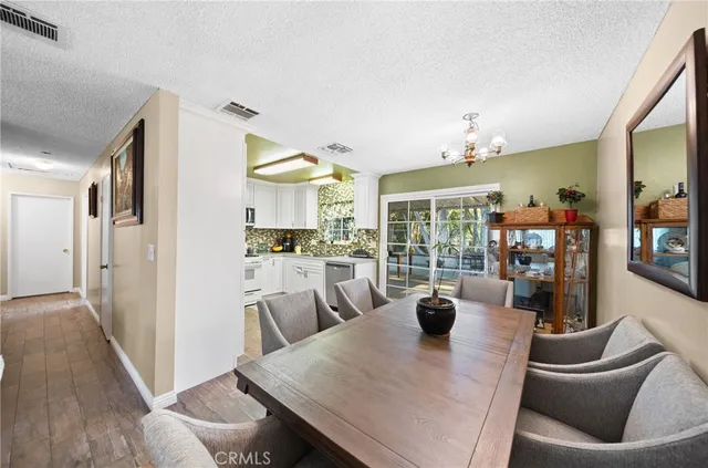a living room with stainless steel appliances furniture a rug and a kitchen view