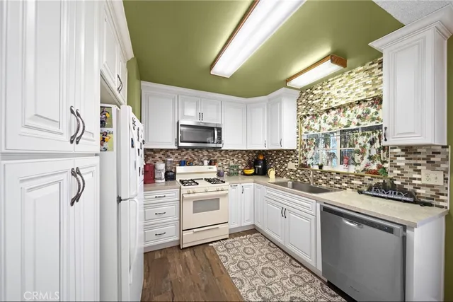 a kitchen with stainless steel appliances granite countertop a sink a stove a refrigerator and cabinets