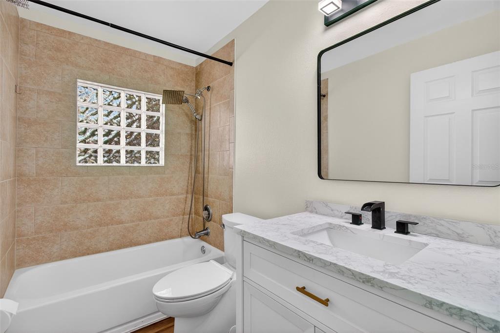 2174 19th Avenue Southwest Largo, FL 33774 - Photo 14 of 31 a bathroom with a granite countertop sink a toilet a mirror and shower
