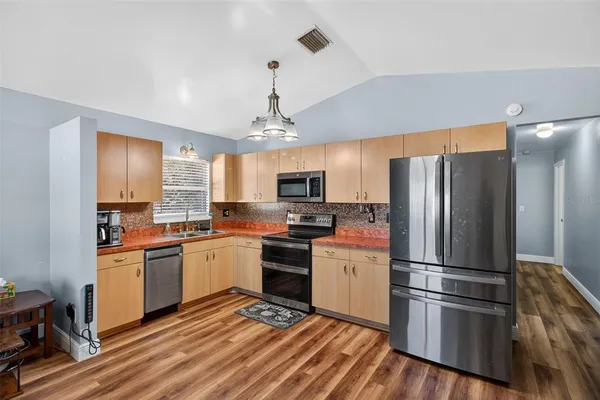 a kitchen with stainless steel appliances granite countertop a refrigerator a stove top oven a sink and dishwasher