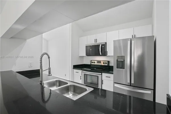 a kitchen with stainless steel appliances granite countertop a refrigerator a stove and a sink