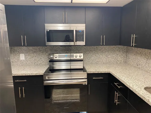 a kitchen with granite countertop a stove and a microwave