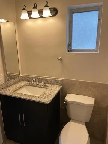 a bathroom with a granite countertop toilet sink and mirror