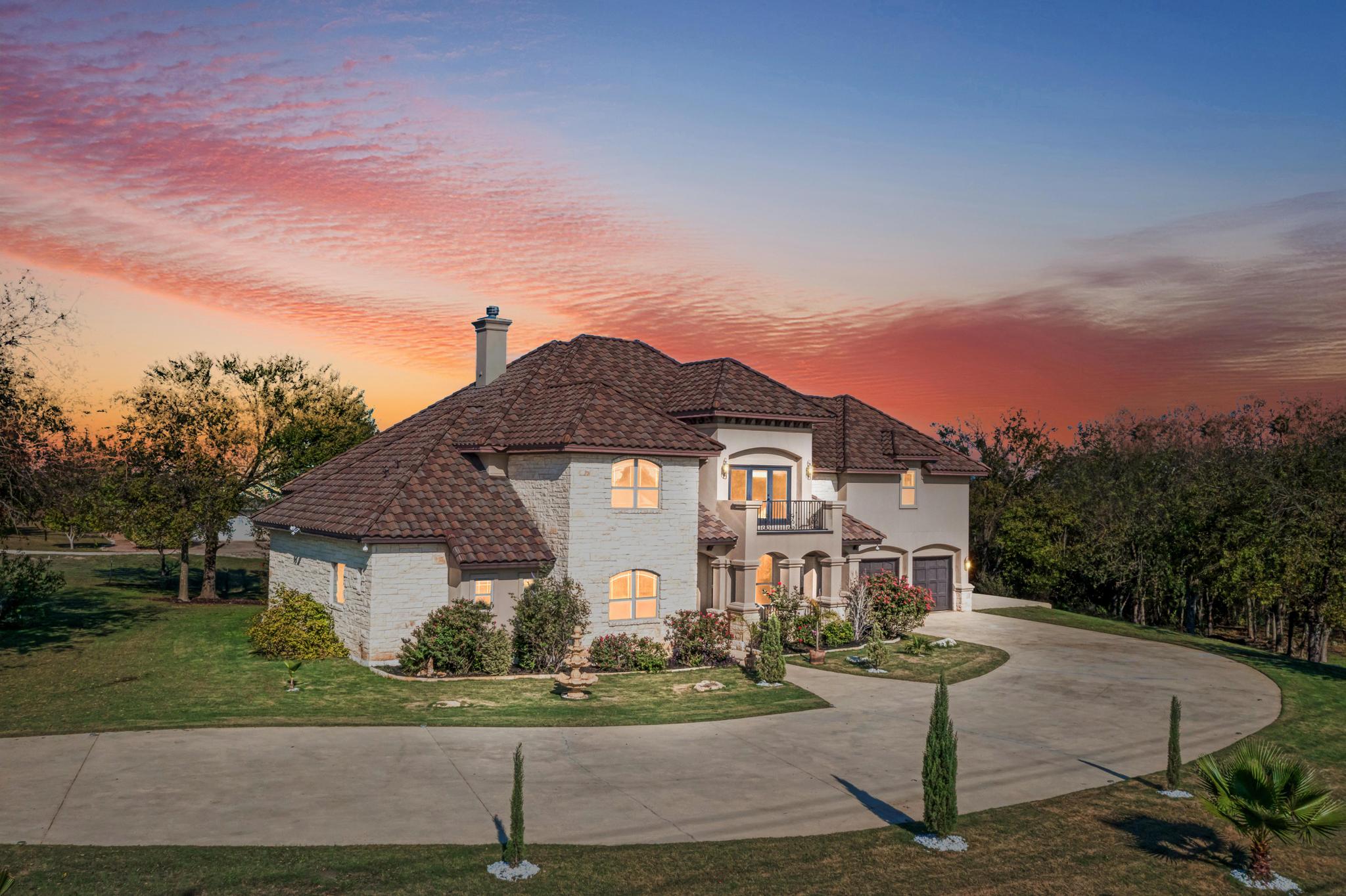 104 Spring Valley Street Hutto, TX 78634 - Photo 1 of 40 View of front of house featuring curved driveway, a balcony, a chimney, stucco siding, and a garage
