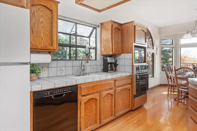 a kitchen with stainless steel appliances granite countertop a stove a sink dishwasher and cabinets with wooden floor