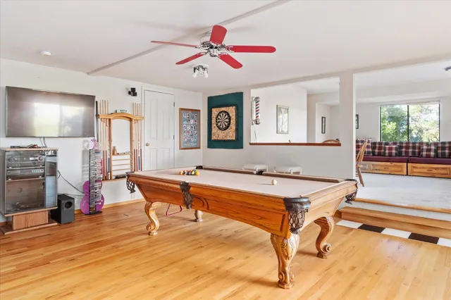 a living room with table a pool table and a large window