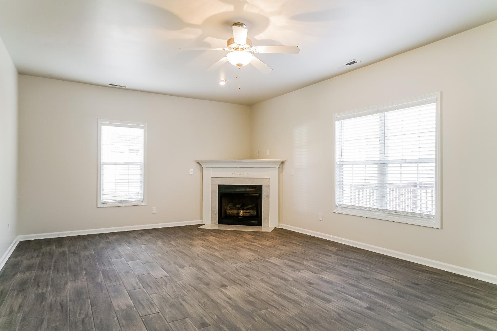 an empty room with windows fireplace and a wooden floor