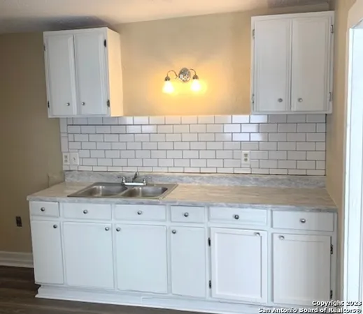 a kitchen with white cabinets and sink