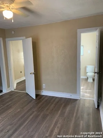 a view of a hallway with wooden floor and a bathroom