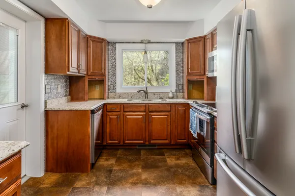 a kitchen with granite countertop a stove top oven cabinetry a sink and a window