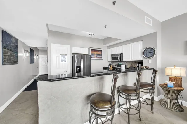 a kitchen with stainless steel appliances granite countertop a refrigerator a stove a sink dishwasher a dining table and chairs with wooden floor