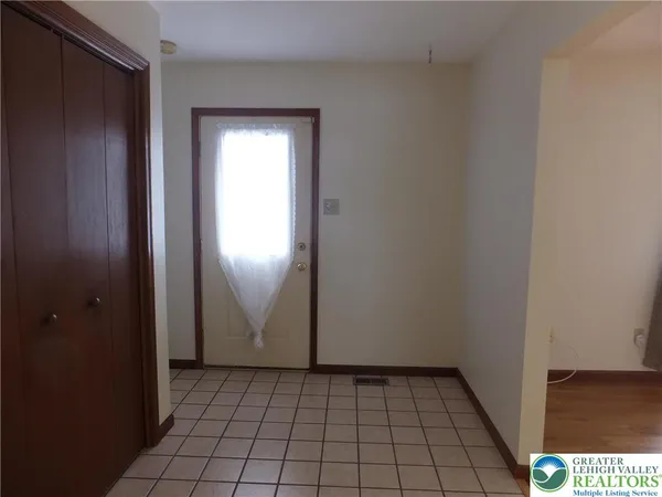 a view of an empty room with closet and window