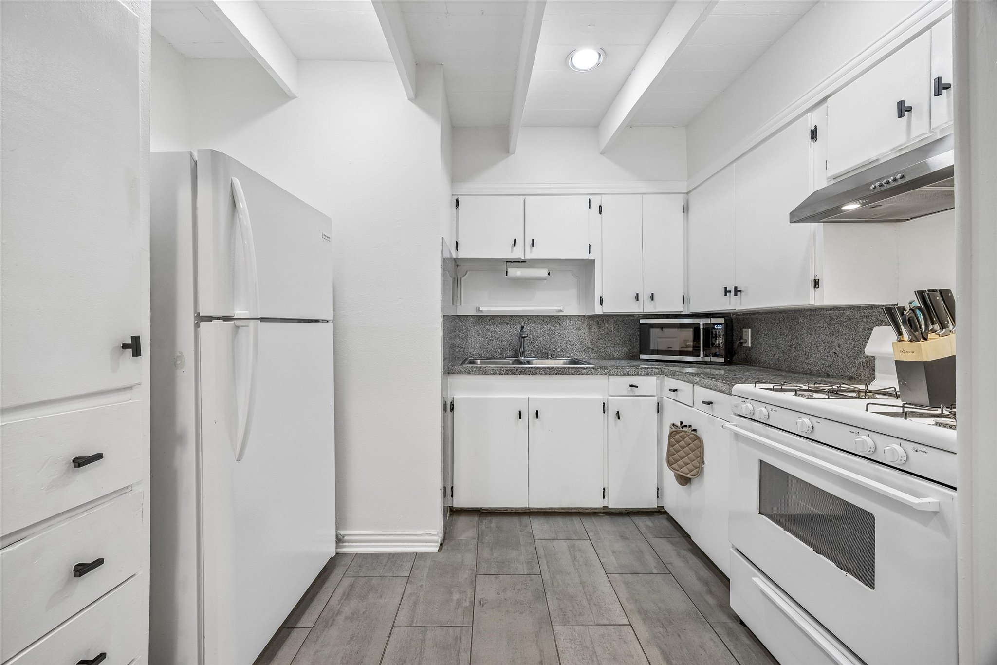 211 Lessin Lane, Unit B Austin, TX 78704 - Photo 8 of 16 Well-appointed kitchen featuring white cabinetry, a white refrigerator, a gas range, and a microwave