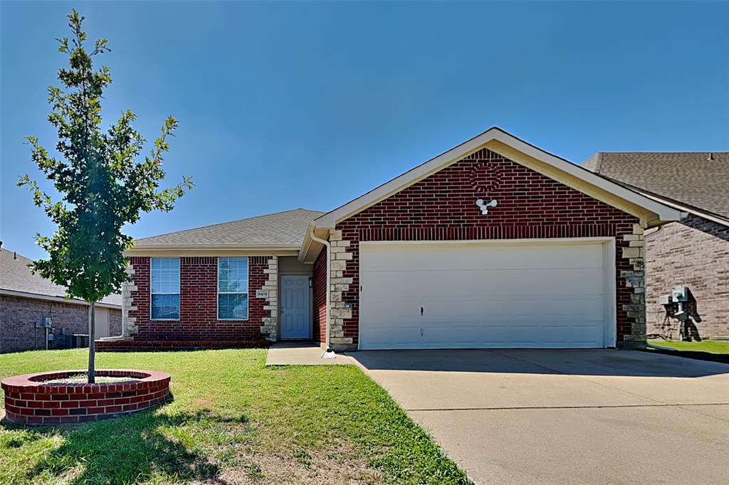 Ranch-style house featuring a garage, concrete driveway, brick siding, and a front lawn