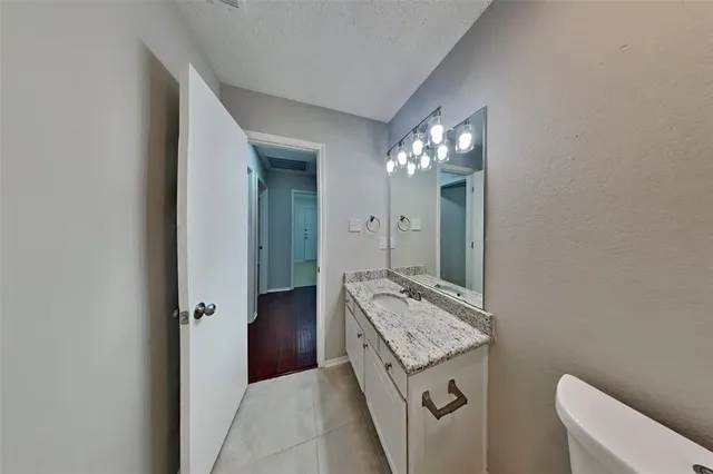 a bathroom with a granite countertop sink a toilet and a mirror