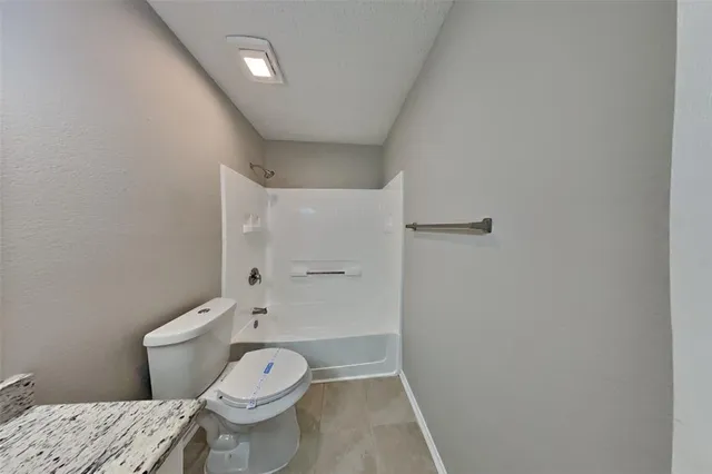 a bathroom with a granite countertop toilet and a shower