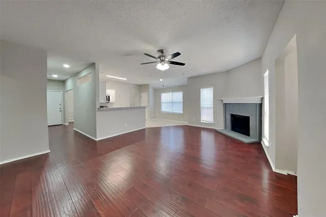 a view of an empty room with wooden floor and a fireplace