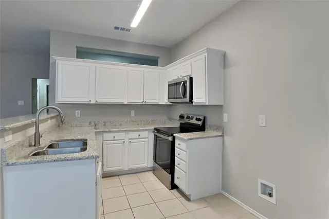 a kitchen with stainless steel appliances granite countertop a sink and dishwasher a stove top oven with white cabinets
