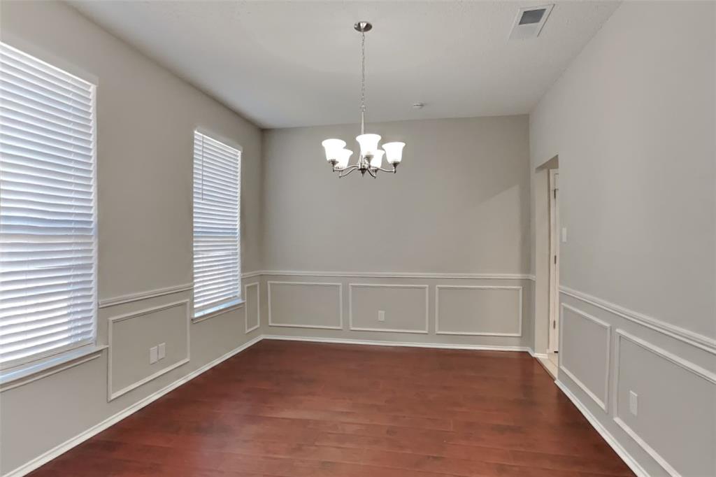 8404 Trinity Vista Trail Fort Worth, TX 76053 - Photo 5 of 18 Unfurnished dining area featuring a chandelier, dark wood finished floors, a decorative wall, and wainscoting