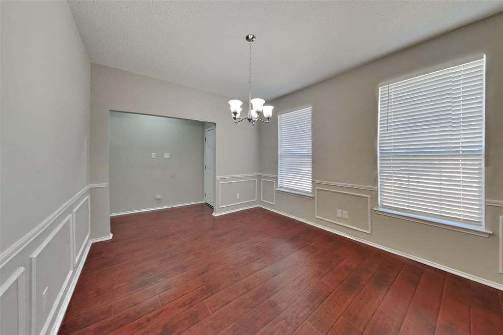 8404 Trinity Vista Trail Fort Worth, TX 76053 - Photo 6 of 18 Unfurnished dining area featuring a decorative wall, a chandelier, dark wood-type flooring, and wainscoting