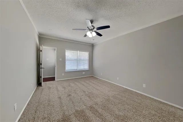 an empty room with chandelier fan and windows