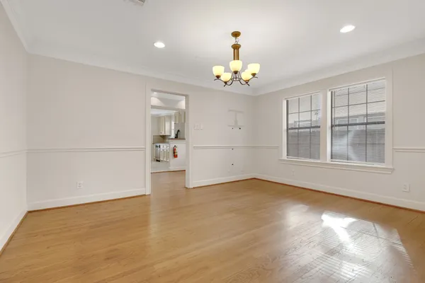 an empty room with wooden floor and chandelier